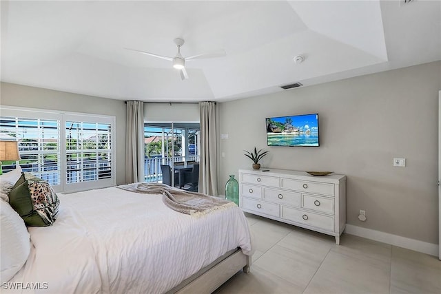 tiled bedroom with access to exterior, a tray ceiling, and ceiling fan