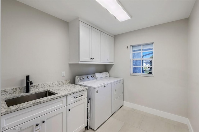 laundry room with cabinets, washing machine and dryer, light tile patterned flooring, and sink