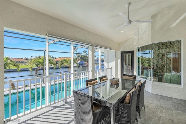 sunroom featuring ceiling fan, a water view, a healthy amount of sunlight, and lofted ceiling