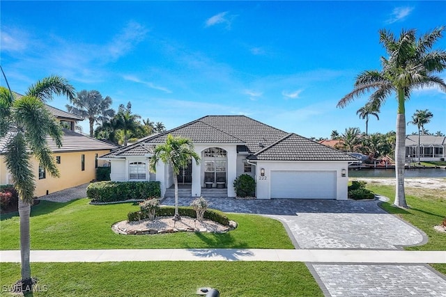 mediterranean / spanish-style house with a garage, a water view, and a front yard