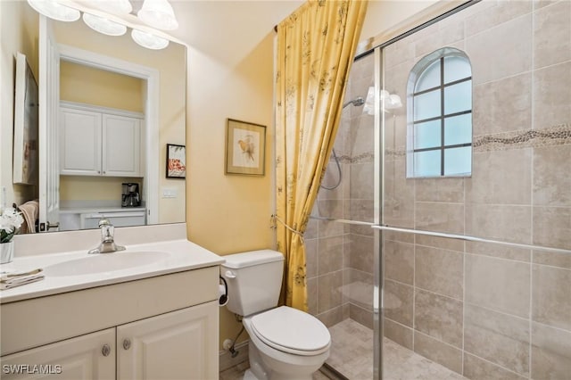 bathroom featuring vanity, toilet, and a shower with shower door