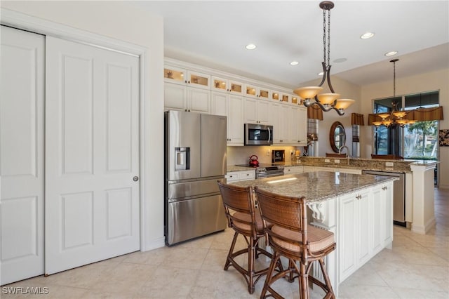 kitchen with stainless steel appliances, light stone counters, kitchen peninsula, pendant lighting, and a kitchen island