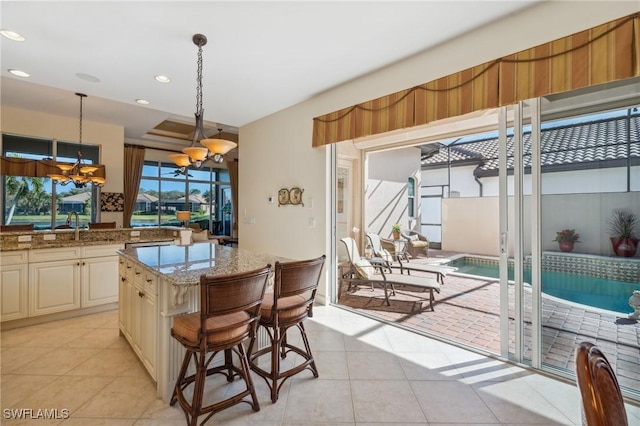 kitchen with light stone counters, pendant lighting, light tile patterned flooring, and a chandelier