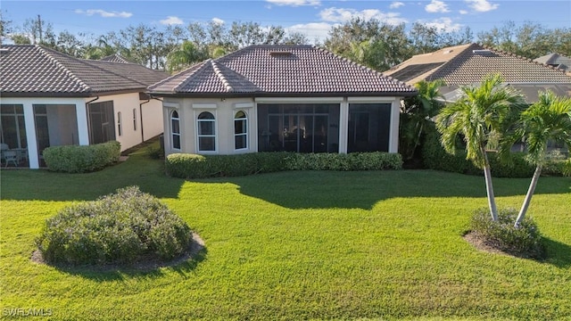 rear view of house featuring a sunroom and a yard