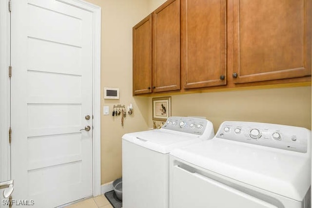 laundry area featuring washer and dryer, light tile patterned floors, and cabinets