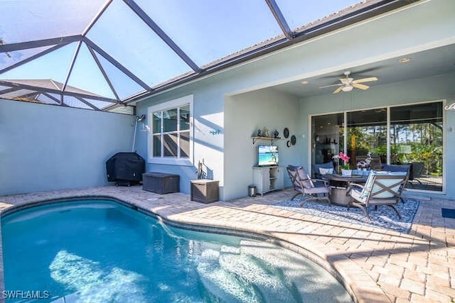 view of pool featuring ceiling fan, a grill, a patio area, and glass enclosure