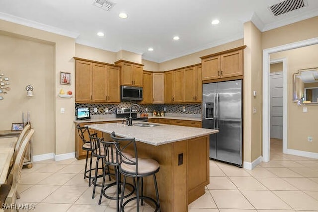 kitchen with appliances with stainless steel finishes, tasteful backsplash, a kitchen island with sink, crown molding, and sink