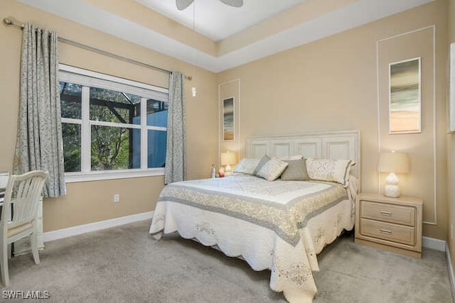 carpeted bedroom with ceiling fan and a raised ceiling