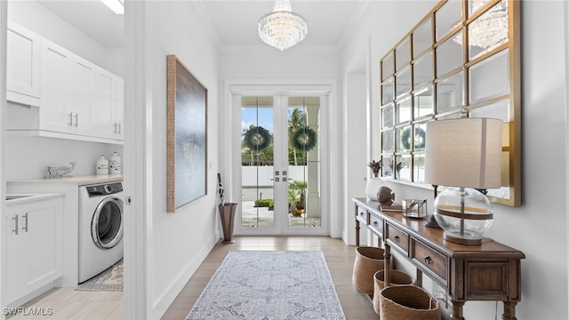 clothes washing area featuring cabinets, french doors, crown molding, a notable chandelier, and washer / clothes dryer