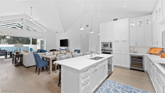 kitchen with white cabinets, high vaulted ceiling, stainless steel appliances, and beverage cooler