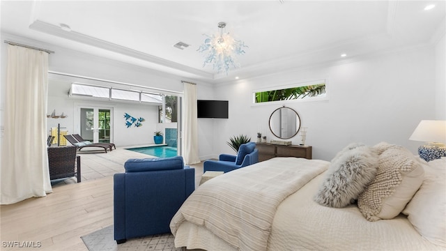 bedroom with light hardwood / wood-style floors, ornamental molding, and a tray ceiling