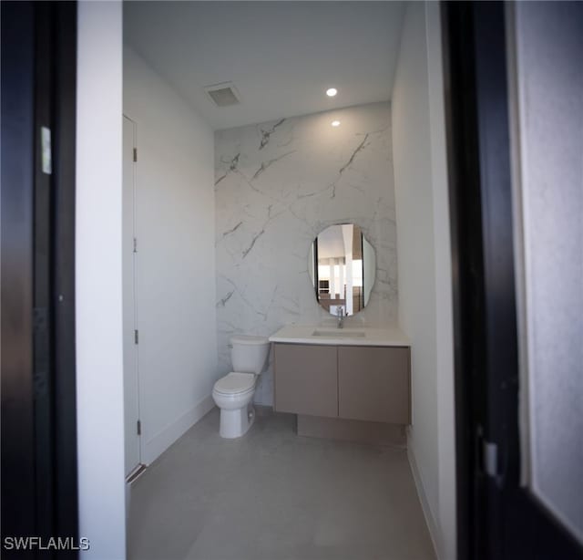 bathroom with vanity, toilet, and tile walls