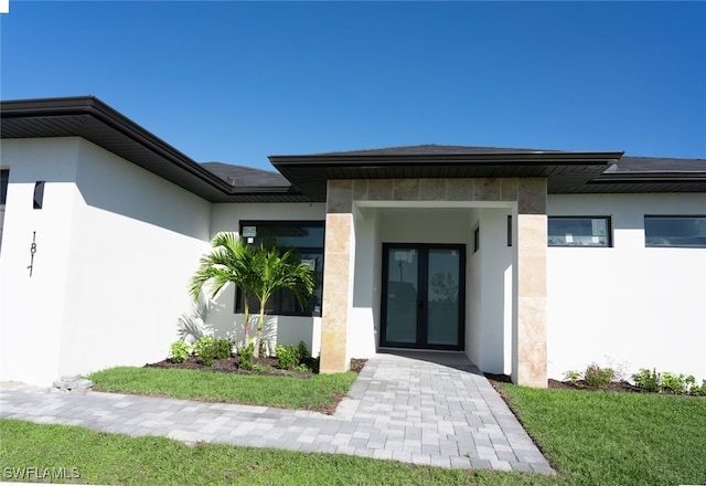 property entrance featuring a lawn and french doors