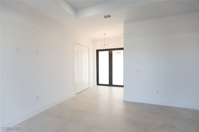 unfurnished room featuring french doors and an inviting chandelier