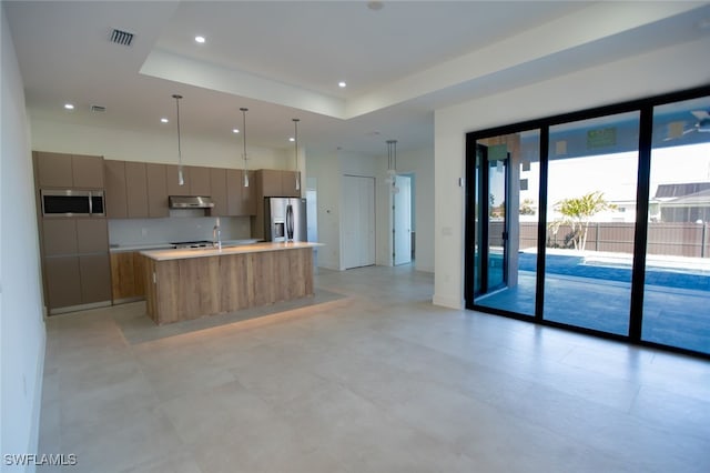 kitchen featuring tasteful backsplash, appliances with stainless steel finishes, a raised ceiling, pendant lighting, and a large island