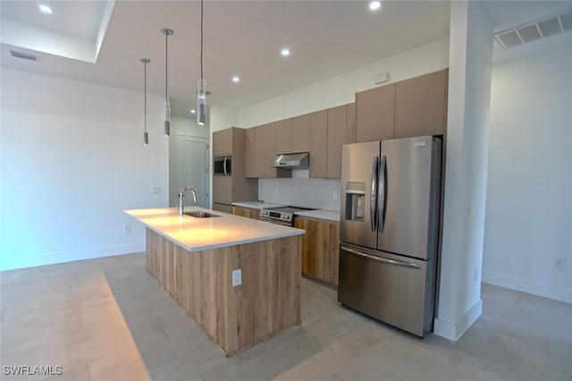 kitchen featuring sink, hanging light fixtures, a center island with sink, stainless steel appliances, and backsplash