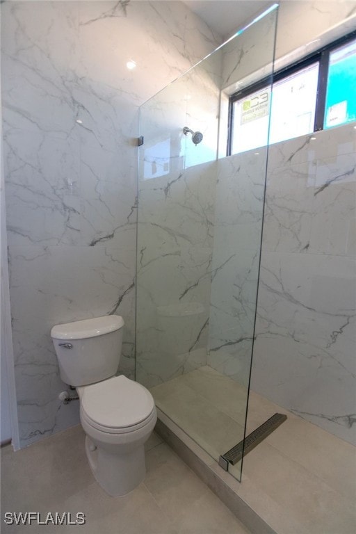 bathroom with tile patterned floors, toilet, and a tile shower