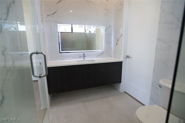 bathroom with vanity, toilet, and a shower with door