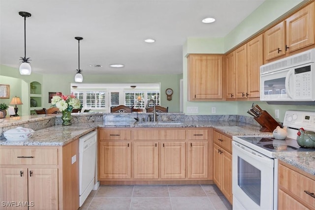 kitchen featuring light brown cabinetry, white appliances, hanging light fixtures, and sink