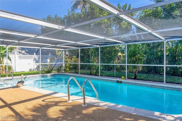 view of pool with glass enclosure and a patio