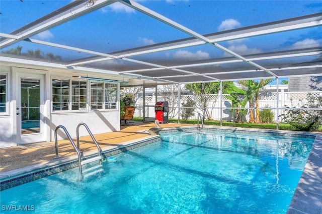 view of pool featuring glass enclosure, grilling area, and a patio area