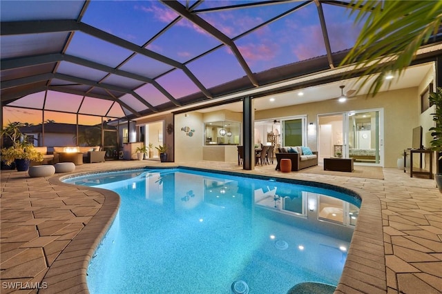 pool at dusk with an outdoor hangout area, glass enclosure, and a patio area