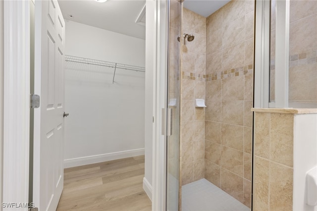 bathroom with tiled shower and hardwood / wood-style floors