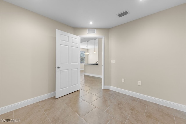 spare room with light tile patterned floors and a chandelier