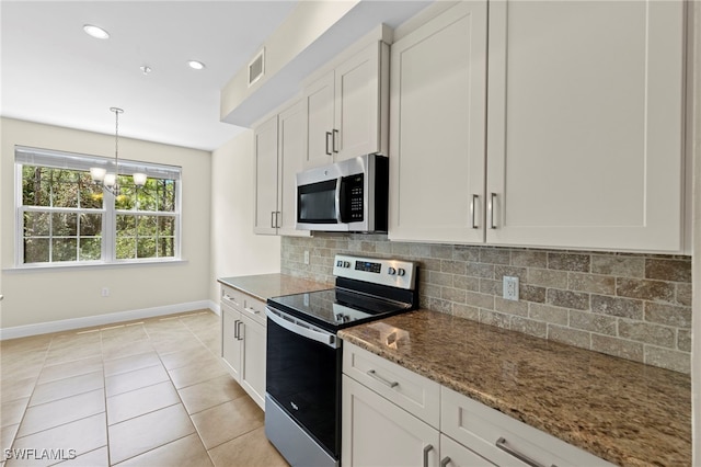 kitchen featuring an inviting chandelier, tasteful backsplash, dark stone counters, white cabinets, and appliances with stainless steel finishes