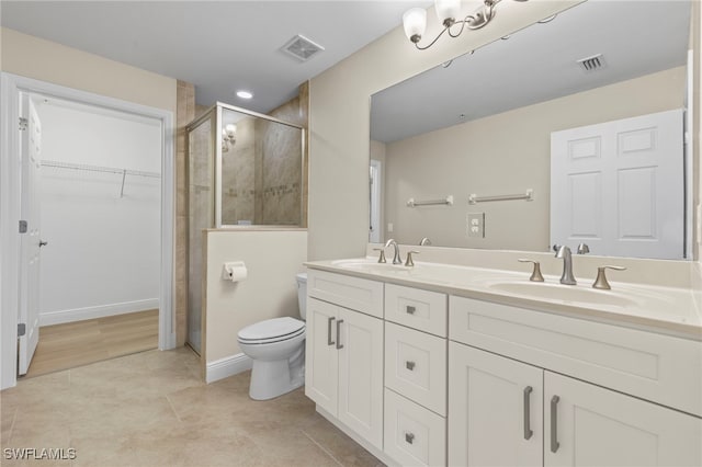 bathroom featuring tile patterned flooring, vanity, toilet, and a shower with door