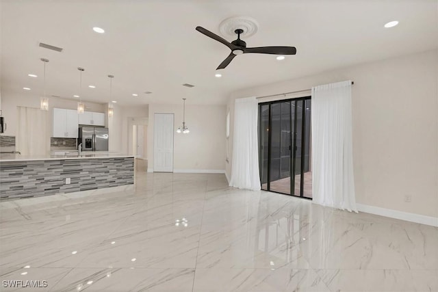 unfurnished living room featuring sink and ceiling fan with notable chandelier