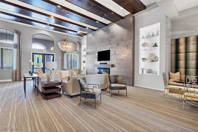 living room featuring a fireplace, beam ceiling, built in features, and a notable chandelier