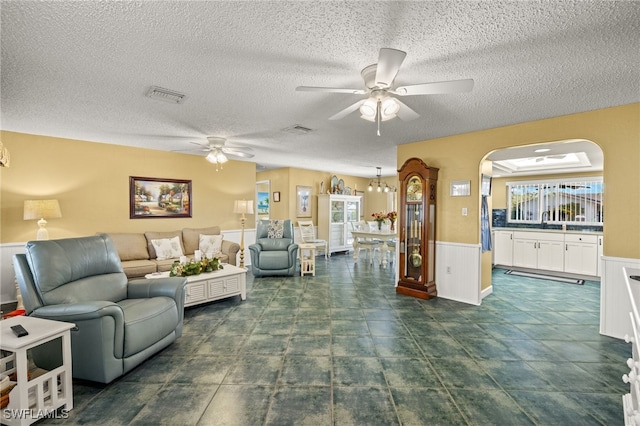 living room featuring ceiling fan, sink, and a textured ceiling