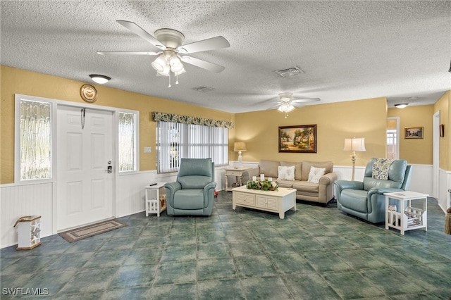 living room with ceiling fan and a textured ceiling