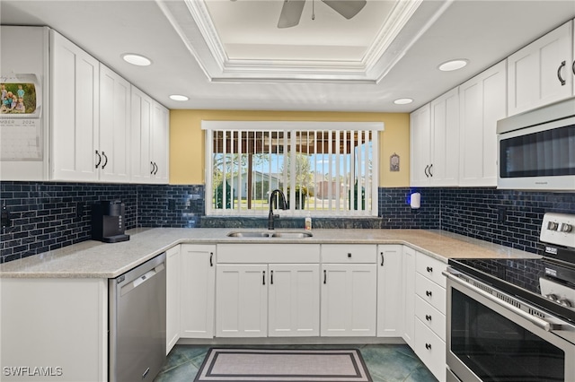 kitchen with white cabinets, stainless steel appliances, a tray ceiling, and sink