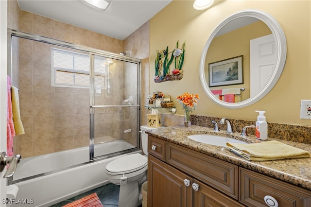 full bathroom with shower / bath combination with glass door, tile patterned floors, vanity, and toilet