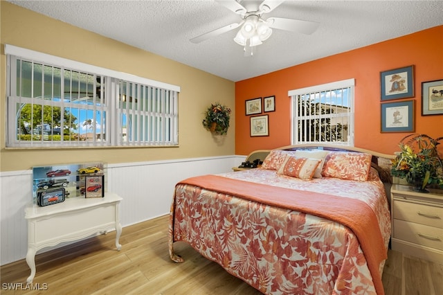 bedroom with a textured ceiling, light wood-type flooring, and ceiling fan