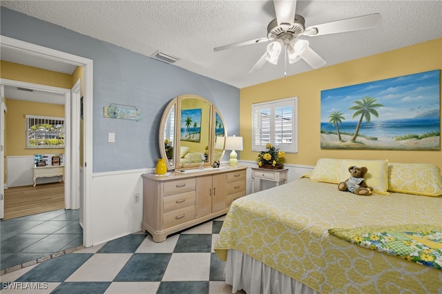 bedroom featuring ceiling fan, light hardwood / wood-style floors, and a textured ceiling