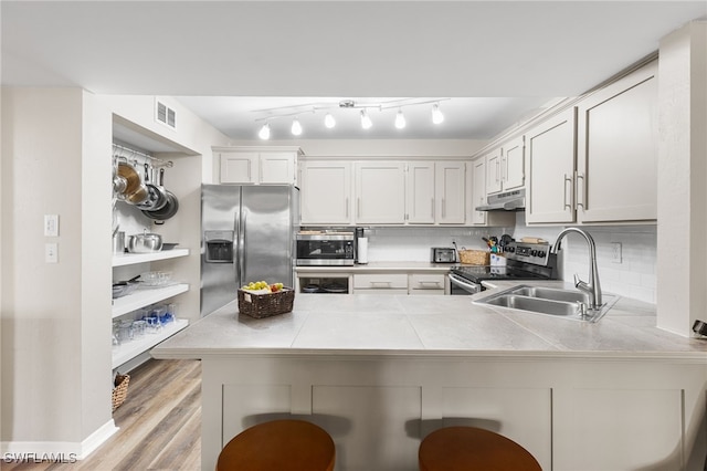 kitchen featuring white cabinets, a kitchen breakfast bar, light hardwood / wood-style flooring, appliances with stainless steel finishes, and kitchen peninsula