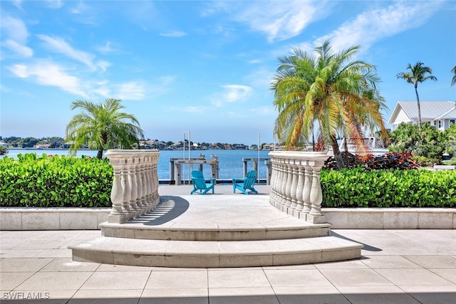 view of community with a patio area, a water view, and a boat dock