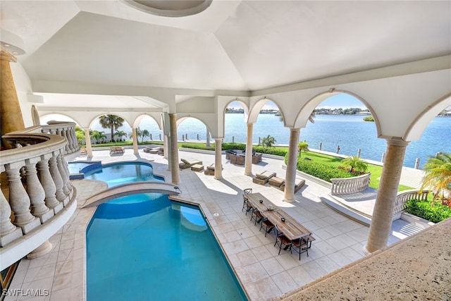 view of swimming pool with an in ground hot tub, a water view, and a patio