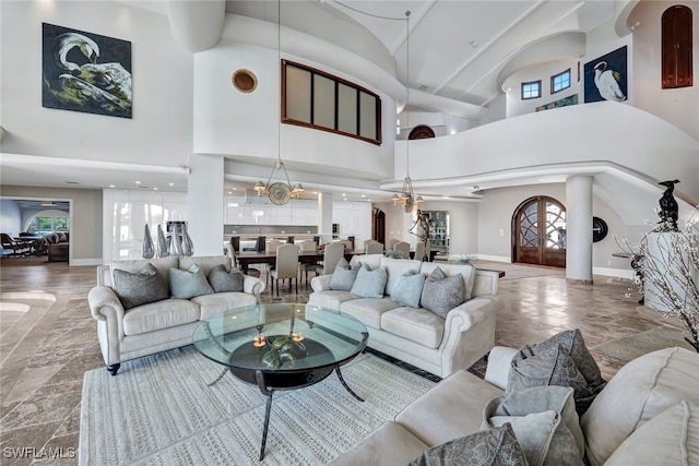 living room featuring a notable chandelier, a towering ceiling, and french doors