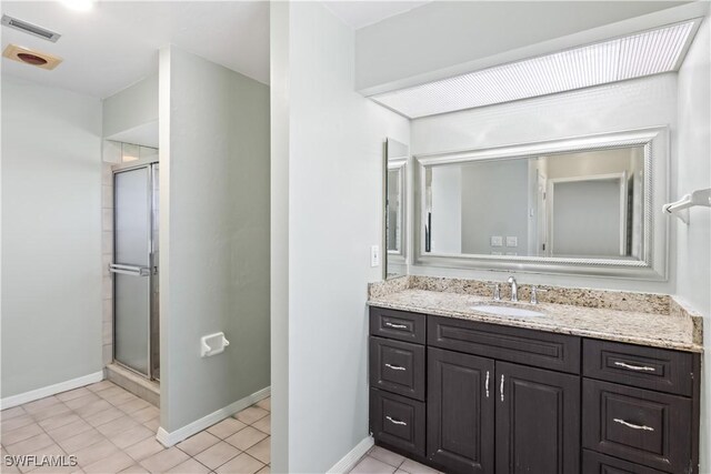 bathroom with walk in shower, vanity, and tile patterned flooring