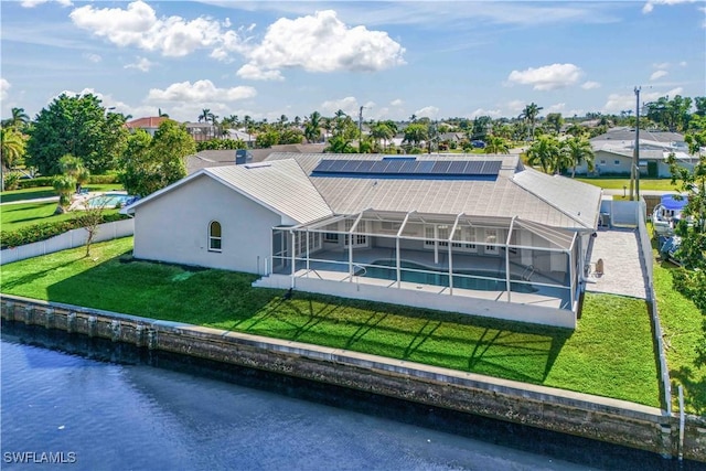 back of house featuring a yard, a water view, and glass enclosure