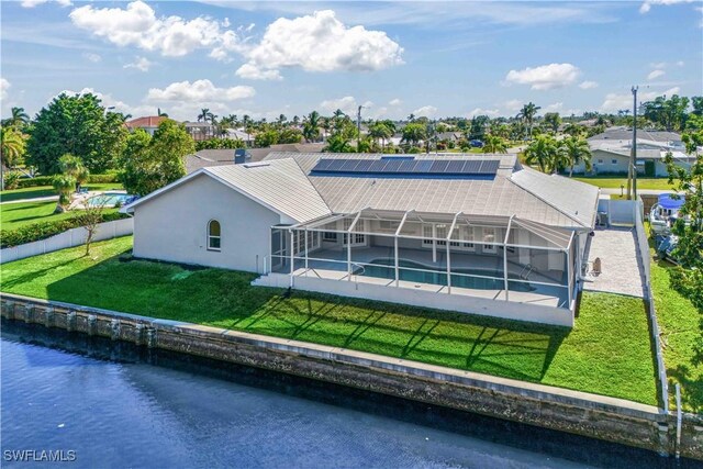 back of house with a water view, a yard, and a lanai