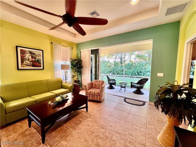 tiled living room featuring a raised ceiling and ceiling fan