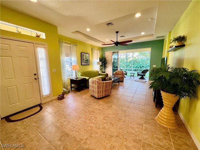 interior space featuring tile patterned flooring, ceiling fan, and a tray ceiling