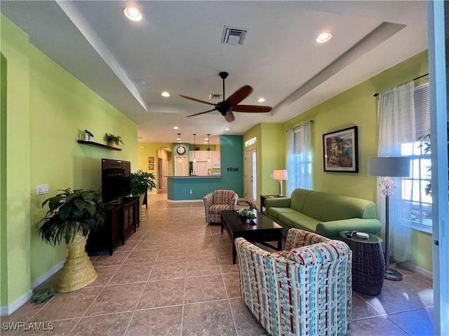 tiled living room featuring a raised ceiling and ceiling fan