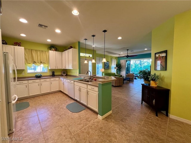 kitchen featuring decorative light fixtures, white cabinetry, sink, kitchen peninsula, and white appliances