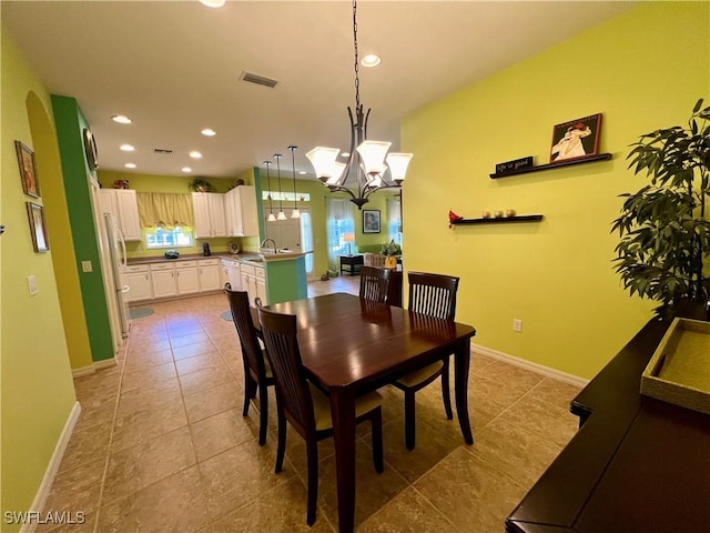 dining area featuring light tile patterned floors, sink, and an inviting chandelier